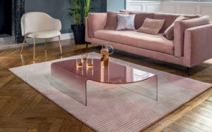 glass coffee table next to pink couch